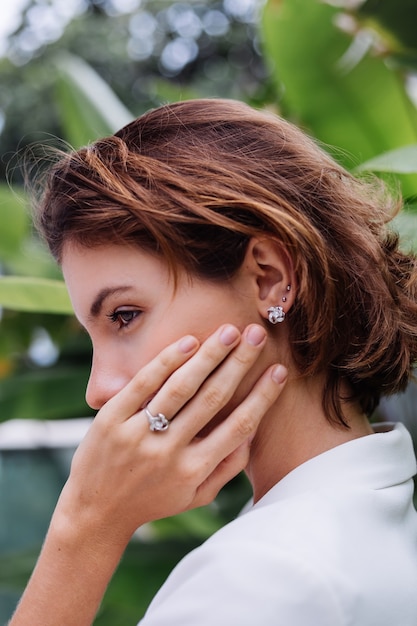 Foto grátis retrato da moda da mulher em uma vila de luxo tropical usando um blazer branco elegante e joias sobre folhas tropicais