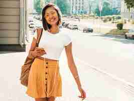 Foto grátis retrato da moda da mulher jovem hippie elegante andando na rua. garota vestindo roupas da moda bonito. modelo sorridente desfrutar de seus fins de semana, viajar com mochila. mulher ouvindo música através de fones de ouvido