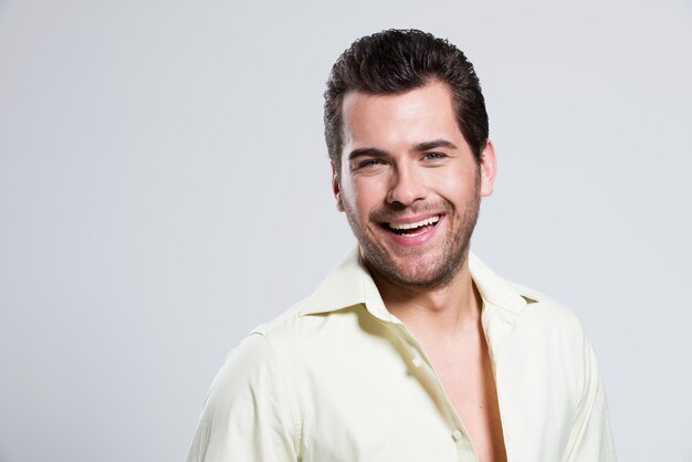 Retrato da moda de homem bonito e feliz em poses de camisa amarela