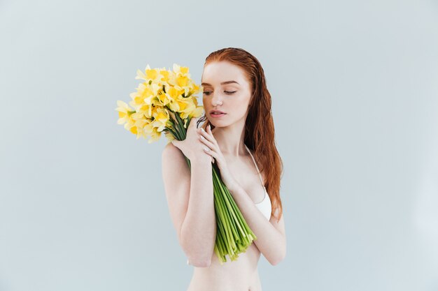 Retrato da moda de uma jovem ruiva segurando flores narcisuss