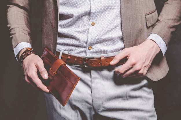 Retrato da moda do homem bonito modelo jovem empresário vestido elegante terno marrom com acessórios