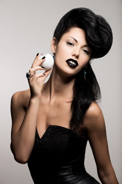 Retrato da moda mulher com penteado moderno e lábios na cor preta com maçã branca