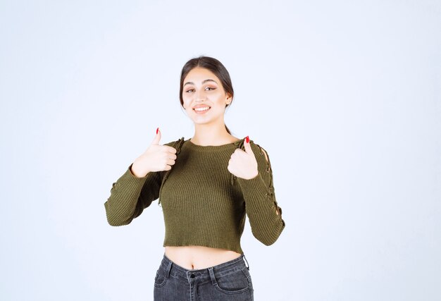 Retrato da modelo de uma jovem mulher bonita dando os polegares para cima