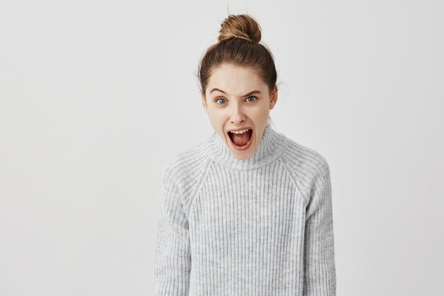 Retrato da mulher furioso que shouting levantando uma sobrancelha. Reação nervosa da diretora de elenco feminina gritando em desacordo. Conceito de emoções