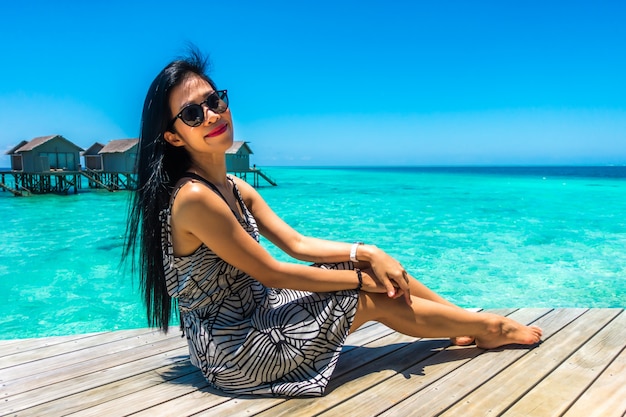 Retrato da mulher nova feliz na casa de campo bonita da água na ilha de maldives. viagens e férias. tiro ao ar livre