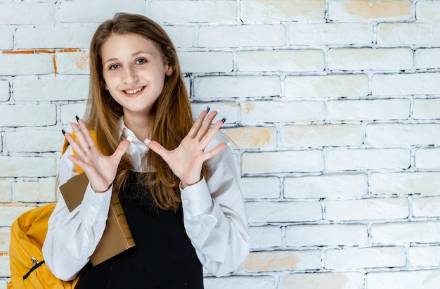 Retrato de adorável estudante sorrindo e mostrando as mãos para a câmera Foto de alta qualidade