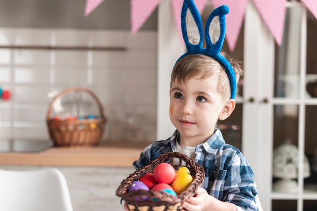 Retrato de adorável menino segurando uma cesta com ovos