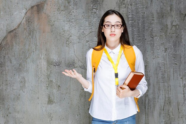 Retrato de aluna de óculos segurando o livro. Foto de alta qualidade