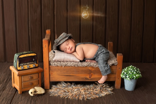 Retrato de bebê recém-nascido de menino agradável e bonito, deitado na pequena cama de madeira, cercada por flores rádio e animal bonito no chão