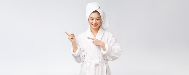 Retrato de beleza de jovem mostrando e apontando o dedo para a beleza asiática do espaço vazio da cópia em roupão de banho