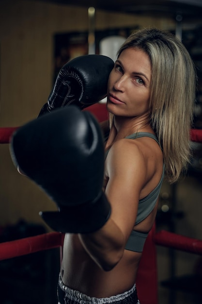 Retrato de boxeador feminino experiente em luvas de boxe e roupas esportivas.