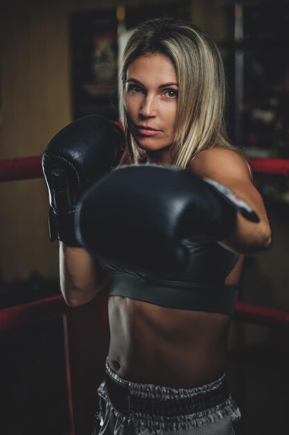 Retrato de boxeador feminino experiente em luvas de boxe e roupas esportivas.