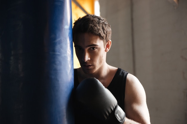 Retrato de boxer perto de punchbag na sombra