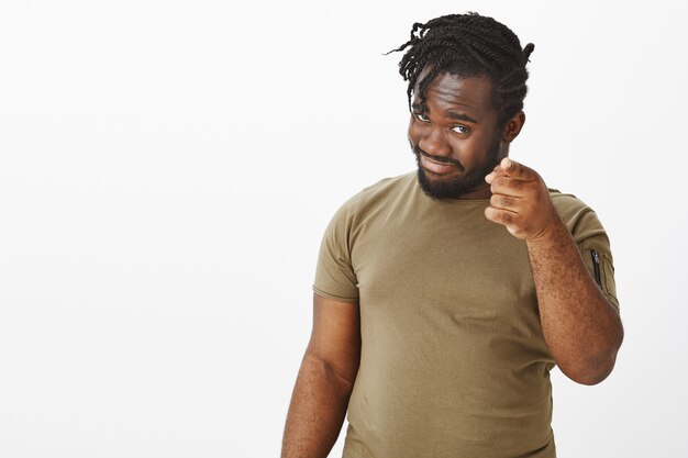 Retrato de cara confiante em uma camiseta marrom posando contra a parede branca
