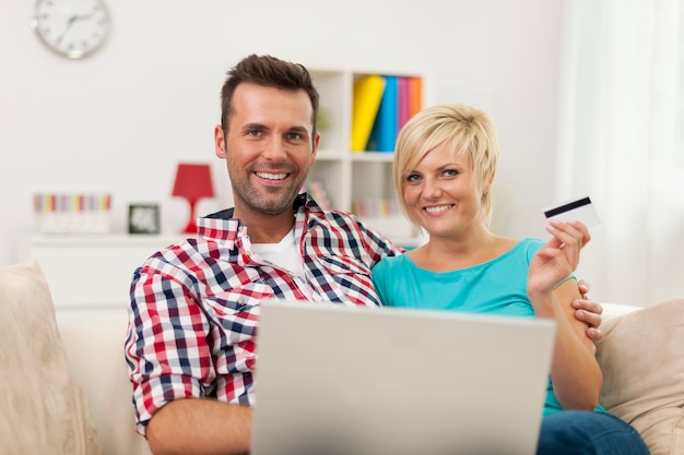 Retrato de casal com laptop e cartão de crédito em casa