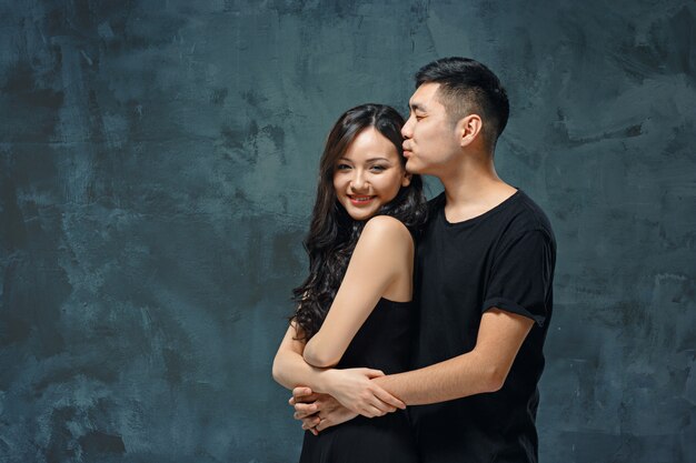 Retrato de casal coreano sorridente em uma parede cinza