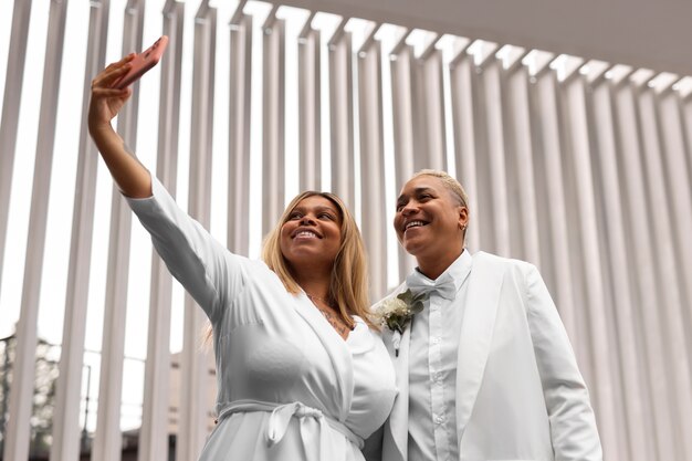 Foto grátis retrato de casal de lésbicas tirando selfie no casamento