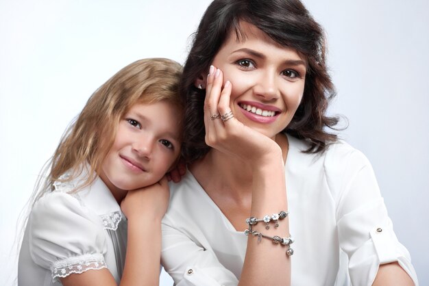 retrato de casal família maravilhoso: linda mãe e sua linda filha. Eles ficam muito felizes com sorrisos bonitos. Eles usam camisetas brancas.