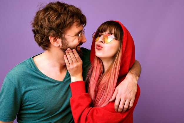 retrato de casal feliz romântico hipster se divertindo juntos, fazendo beijos e abraços, roupas esportivas brilhantes casuais e óculos da moda, melhores amigos juntos.