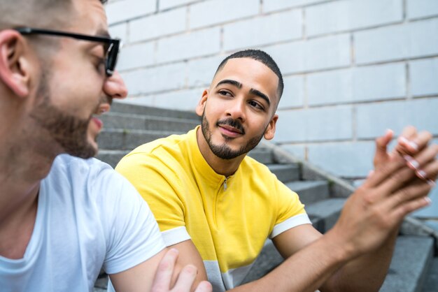 Retrato de casal gay feliz, passando algum tempo juntos enquanto está sentado na escada ao ar livre. Conceito de LGBT e amor.