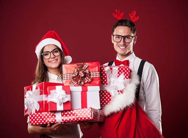 Retrato de casal sorridente com uma pilha de presentes de Natal