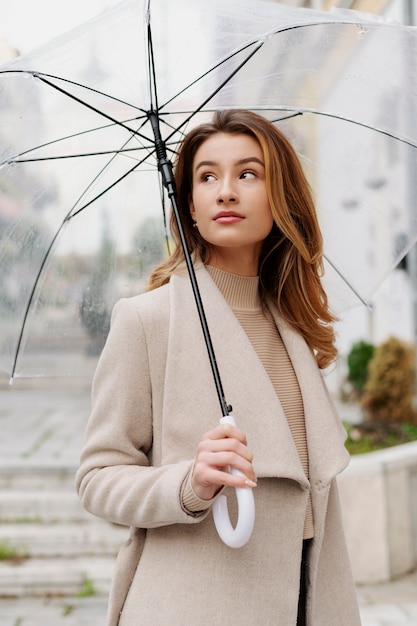 Foto grátis retrato de chuva de uma jovem mulher bonita com guarda-chuva