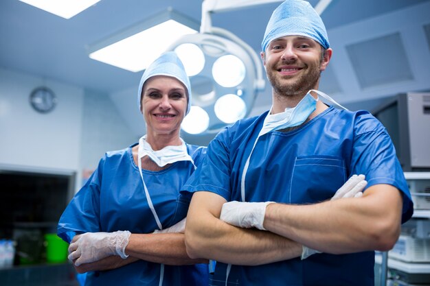 Retrato de cirurgiões que estão com os braços cruzados no quarto de operação