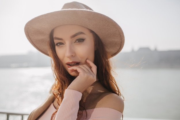 Foto grátis retrato de close-up da fascinante mulher ruiva em pé no paredão