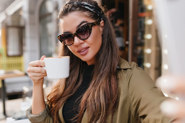 Retrato de close-up de jovem hispânico com fita, desfrutando de café em dia de outono