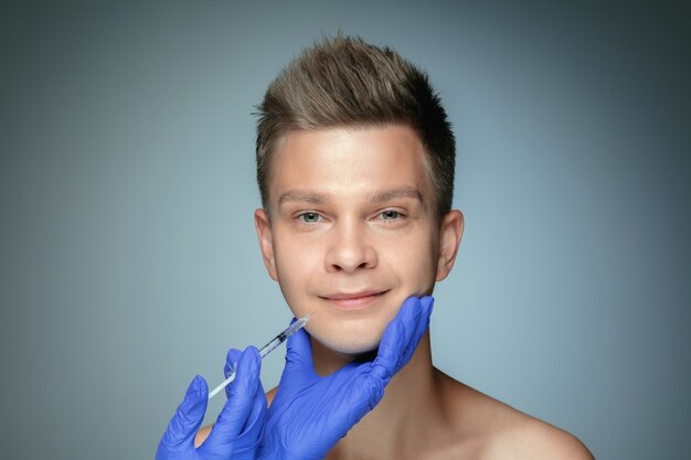 Retrato de close-up de jovem isolado em parede cinza