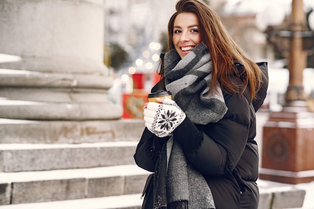 Retrato de close-up de mulher em jaqueta preta com café para viagem