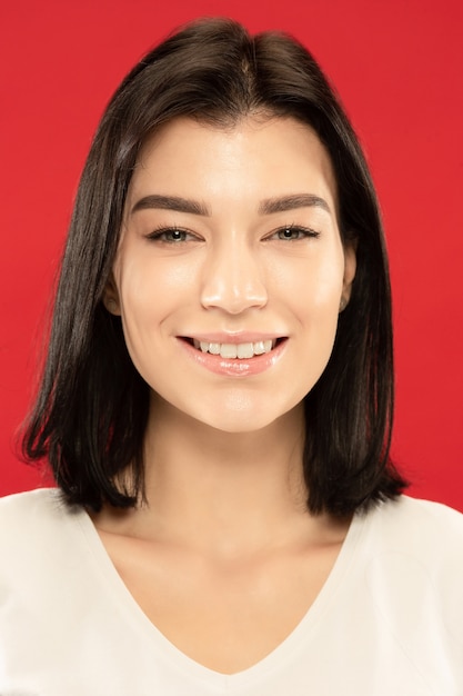 Retrato de close-up de mulher jovem branca no estúdio vermelho