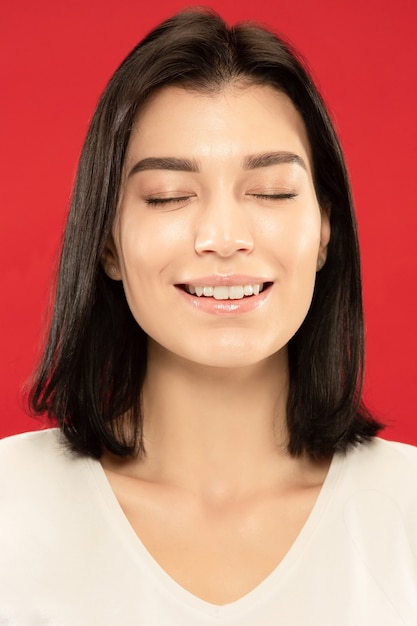 Retrato de close-up de mulher jovem branca no estúdio vermelho