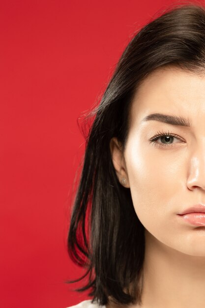 Retrato de close-up de mulher jovem branca no estúdio vermelho