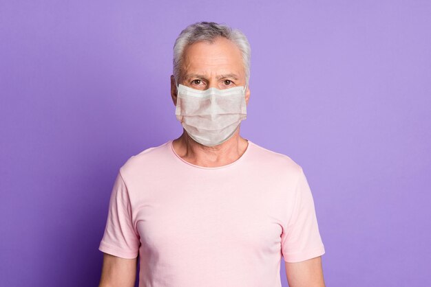 Retrato de close-up de um homem sério usando uma máscara branca isolada sobre um fundo lilás brilhante