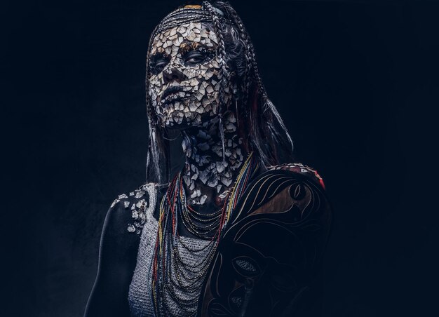 Retrato de close-up de uma fêmea xamã africana da tribo indígena africana, vestindo traje tradicional. Conceito de maquiagem. Isolado em um fundo escuro.