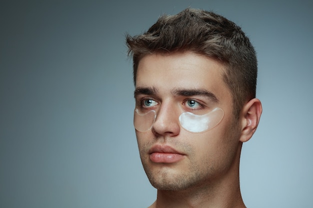 Foto grátis retrato de close-up do perfil de jovem isolado em estúdio cinza