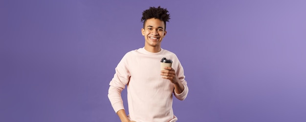 Retrato de conceito de café de estilo de vida comendo de um jovem hispânico alegre segurando uma xícara de café para viagem