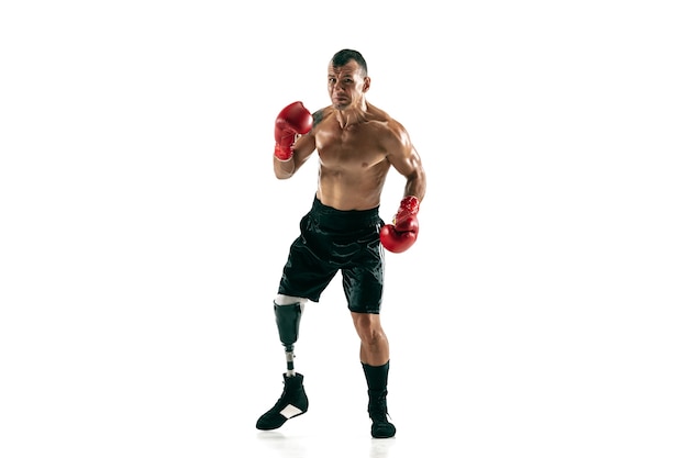 Retrato de corpo inteiro de esportista musculoso com perna protética, copie o espaço. Boxeador masculino em luvas vermelhas. Tiro isolado na parede branca.
