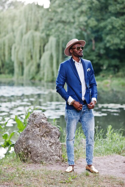 Retrato de corpo inteiro de homem negro elegante no chapéu de jaqueta e óculos de sol