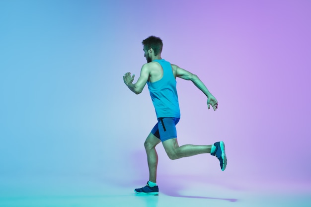 Retrato de corpo inteiro de jovem caucasiano ativo correndo, correndo homem em néon