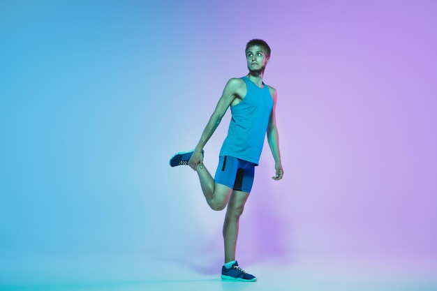 Retrato de corpo inteiro de jovem caucasiano ativo correndo, correndo homem em néon