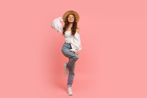 Retrato de corpo inteiro de mulher em elegante top de linho com mangas balão e jeans azul posando em rosa