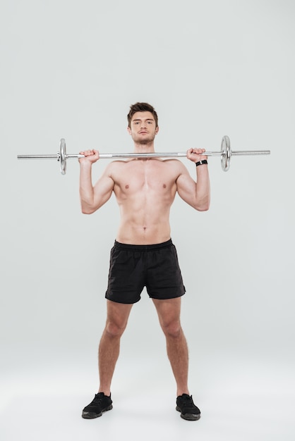 Retrato de corpo inteiro de um desportista apto a levantar barra pesada