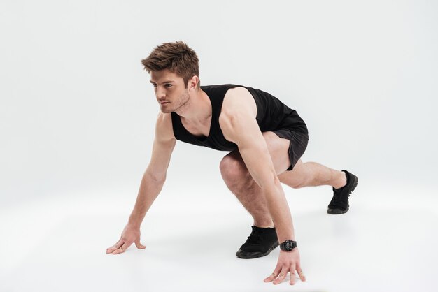 Retrato de corpo inteiro de um esportista concentrado pronto para correr
