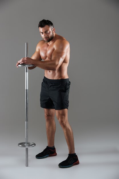 Retrato de corpo inteiro de um fisiculturista masculino sem camisa sério muscular