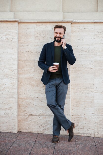 Retrato de corpo inteiro de um homem sorridente segurando a xícara de café