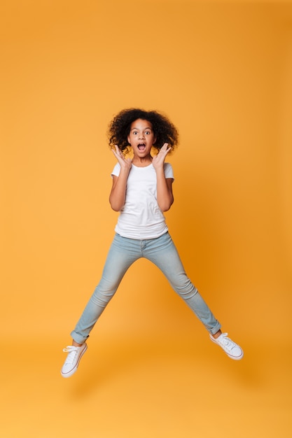 Retrato de corpo inteiro de uma menina africana animada pulando