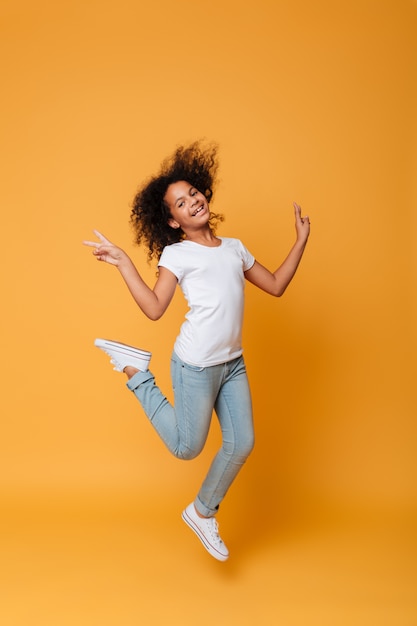Retrato de corpo inteiro de uma menina africana sorridente pulando