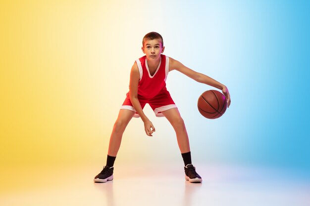 Retrato de corpo inteiro do jovem jogador de basquete de uniforme na parede gradiente